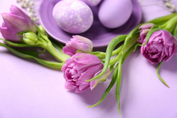 Plate with Easter eggs and tulips on color background Royalty Free Stock Photos