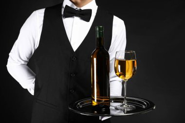 Koyu arka plan üzerinde şarap ile yakışıklı garson