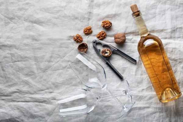 Botella de vino, vasos vacíos y nueces sobre tela ligera — Foto de Stock