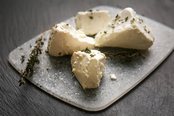 Board with tasty feta cheese and thyme on dark table — Stock Photo, Image