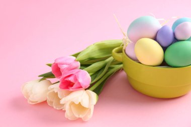Güzel Paskalya yumurtaları ve çiçeklerle renk arka plan üzerinde kase