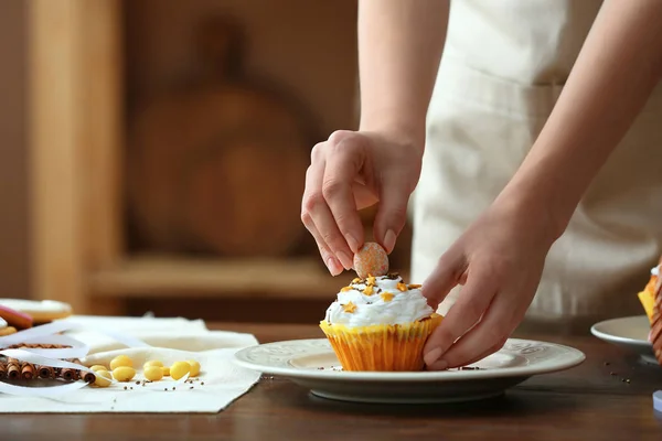 Woman decorating tasty Easter cupcake — Stock Photo, Image