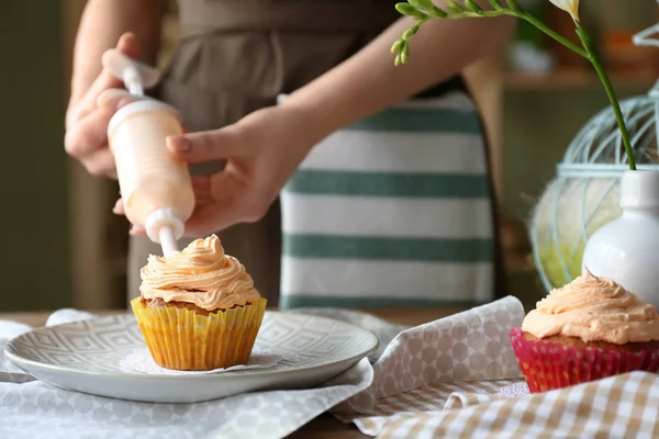 Woman preparing tasty Easter cupcake in kitchen — Stock Photo, Image