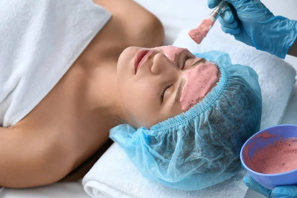 Cosmetólogo aplicando máscara de alginato en la cara de la joven en el salón de belleza — Foto de Stock