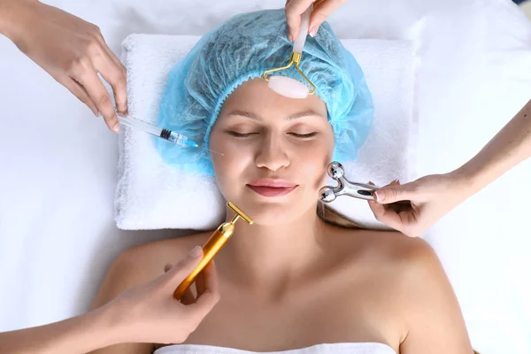 Young woman with different cosmetic devices in beauty salon — Stock Photo, Image