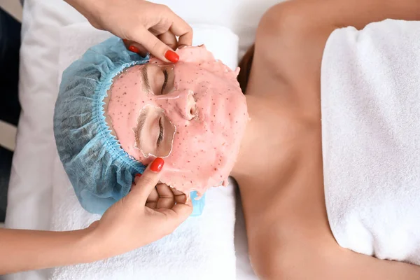 Kosmetolog att ta bort alginat mask från ung kvinnas ansikte i skönhetssalong — Stockfoto