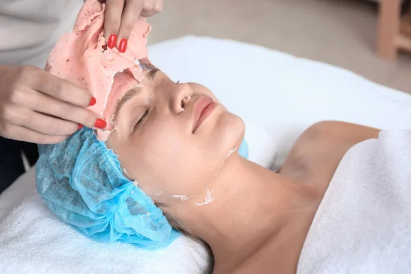 及ぼし美容院における若い女性の顔からアルギン酸マスクを除去する — ストック写真