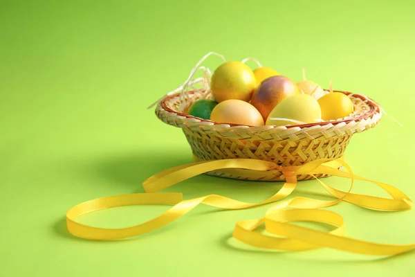 Sombrero con hermosos huevos de Pascua y cinta en el fondo de color — Foto de Stock