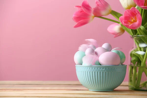 Tál a húsvéti tojás és a virágok, a tábla, színes háttérrel — Stock Fotó