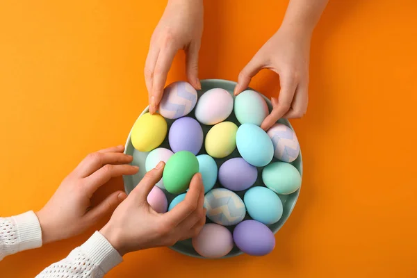 People taking Easter eggs from plate on color background — Stock Photo, Image