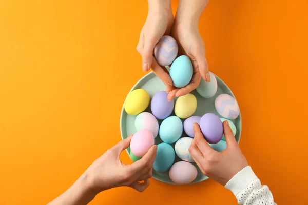 People taking Easter eggs from plate on color background — Stock Photo, Image