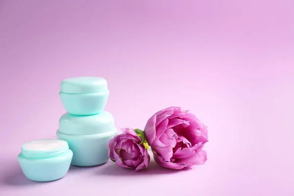 Gläser mit natürlicher Creme mit Tulpen auf farbigem Hintergrund — Stockfoto
