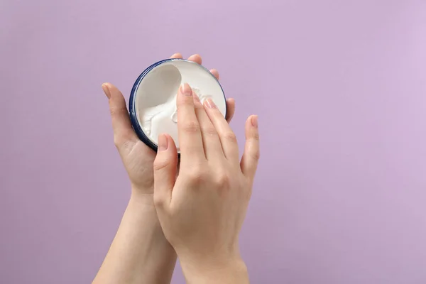 Mani femminili con barattolo di crema naturale su sfondo a colori — Foto Stock
