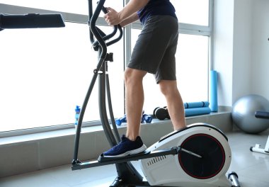 Spor salonunda makine üzerinde sportif genç adam eğitimi