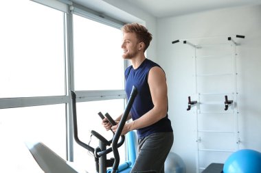 Spor salonunda makine üzerinde sportif genç adam eğitimi