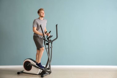 Spor salonunda makine üzerinde sportif genç adam eğitimi