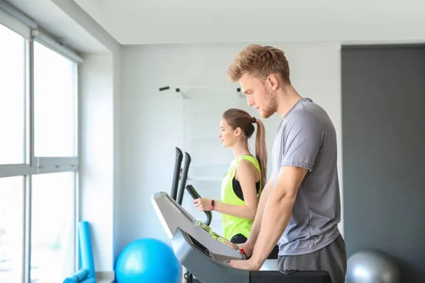Sporty young people training on machines in gym — Stock Photo, Image