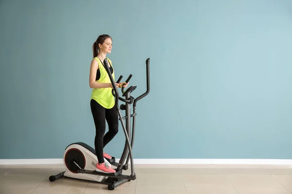 Mujer joven deportiva entrenando en la máquina en el gimnasio — Foto de Stock