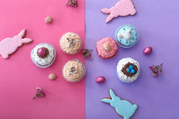 Leckere Oster-Cupcakes mit Keksen auf farbigem Hintergrund — Stockfoto