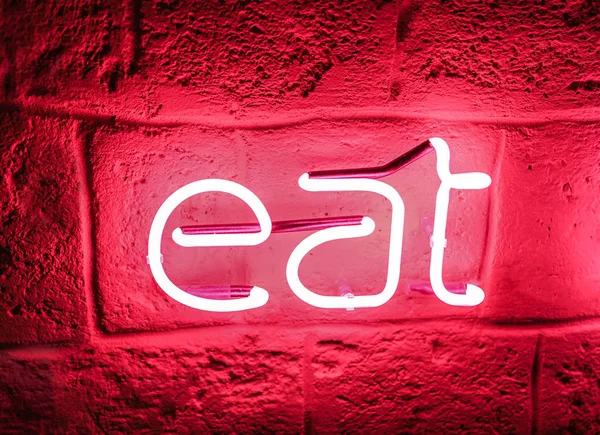 Neon sign on stone wall in darkness