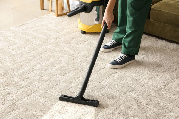 Arbeiter putzt Teppich mit Staubsauger — Stockfoto