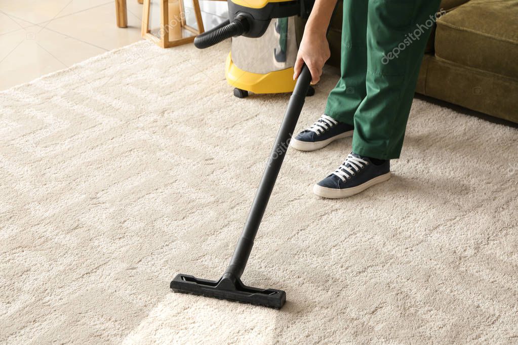 Worker cleaning carpet with hoover