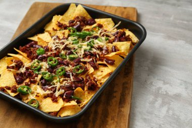 Gri masada lezzetli nachos, kıyılmış et ve Chili ile pişirme çanak