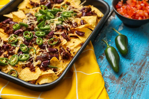 Prato de panificação com nachos saborosos, carne picada e pimenta na mesa de madeira — Fotografia de Stock