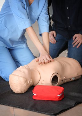 Instructor demonstrating CPR on mannequin at first aid training course clipart