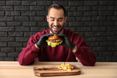 Adam masada patates kızartması ile lezzetli hamburger yeme