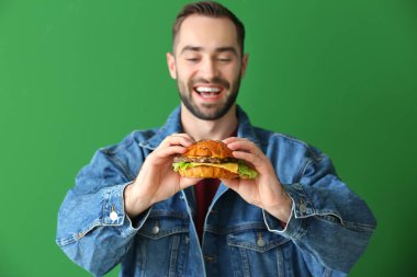 Man renk arka plan üzerinde lezzetli hamburger yemek
