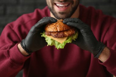 Adam koyu arka plan üzerinde closeup lezzetli hamburger yeme