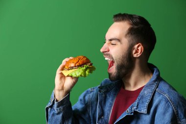 Man renk arka plan üzerinde lezzetli hamburger yemek
