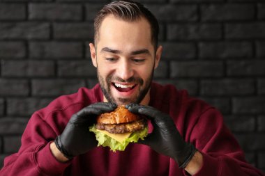Adam koyu arka plan üzerinde lezzetli hamburger yeme