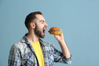 Man renk arka plan üzerinde lezzetli hamburger yemek
