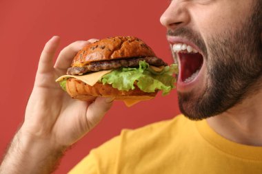 Man renk arka plan üzerinde lezzetli hamburger yemek
