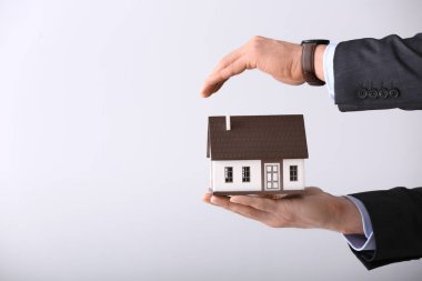 Açık renkli ev modeli ile sigortacı. Deprem evden korunması