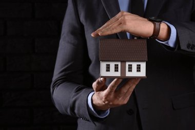 Koyu arka plan, closeup şirketten modeli ile sigortacı. Deprem evden korunması