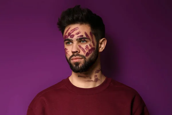 Портрет красивого мужчины с краской на лице на цветном фоне — стоковое фото