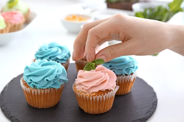 Young female confectioner decorating cupcakes in kitchen, closeup — Stock Photo, Image