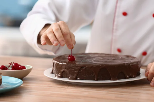 Pasticceria maschile decorazione gustosa torta al cioccolato in cucina, primo piano — Foto Stock