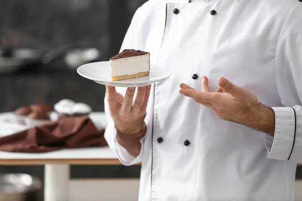 Male confectioner with piece of tasty cake in kitchen — Stock Photo, Image