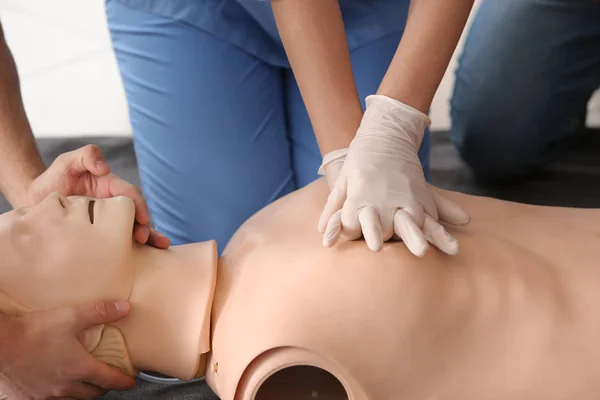 Instructor demonstrating CPR on mannequin at first aid training course