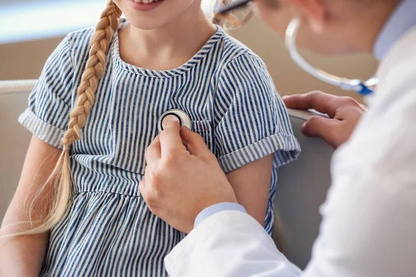 Pediyatrist küçük kızı klinikte muayene ediyor.