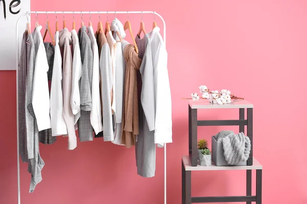 Rack with stylish clothes near color wall in room — Stock Photo, Image