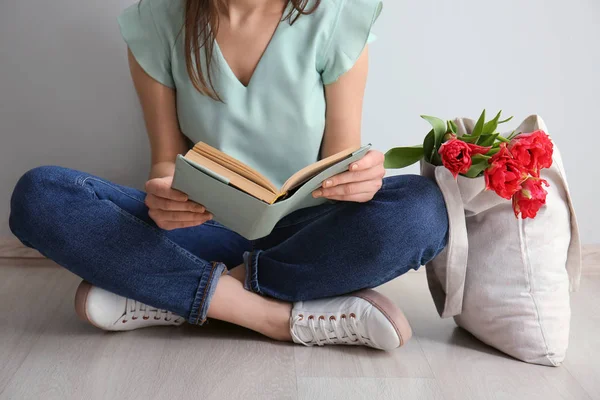 Vrouw met boek en eco-tas zittend op de vloer — Stockfoto