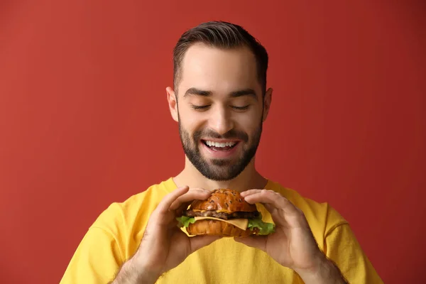 Man with tasty burger on color background — Stock Photo, Image