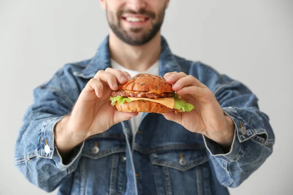 Homme avec hamburger savoureux sur fond clair — Photo