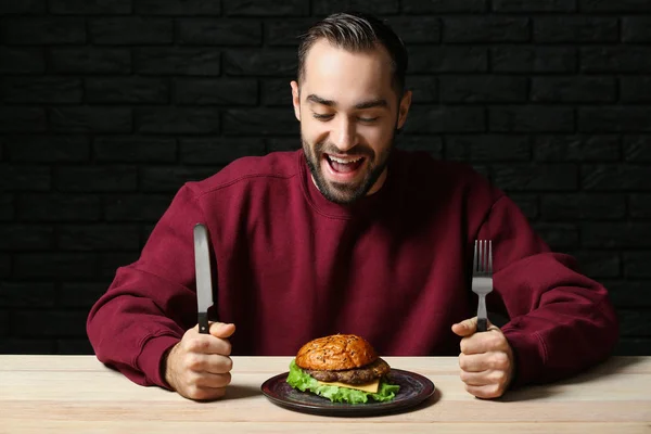 Uomo con gustoso hamburger a tavola — Foto Stock