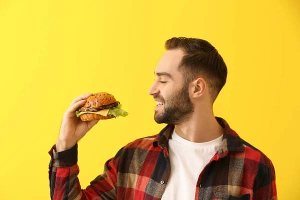 Man with tasty burger on color background — Stock Photo, Image